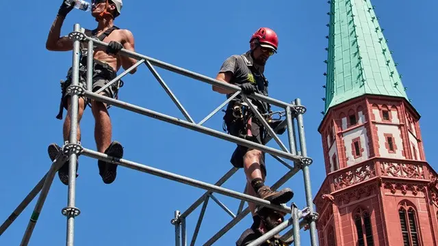 Seorang pekerja minum air saat menyiapkan panggung untuk ajang triathlon Ironman di Frankfurt, Jerman, Kamis (25/6/2026), di tengah gelombang panas yang melanda Eropa.