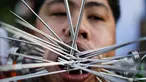Seorang pemuja dari Kuil Samkong menusukkan besi ke pipi saat memeriahkan festival vegetarian di Phuket, Thailand (4/10). Festival ini menampilkan aksi ekstrem pemuja dengan menusukkan benda tajam ke wajah. (REUTERS/Jorge Silva)