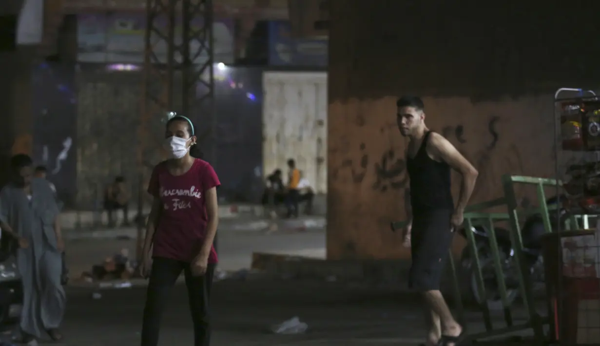 Seorang gadis memakai masker wajah setelah berbelanja dari toko bahan makanan selama penguncian yang diberlakukan selama pandemi virus corona, di kamp pengungsi Shati, di Kota Gaza, Selasa, (1/9/2020). (AP Photo/Adel Hana)