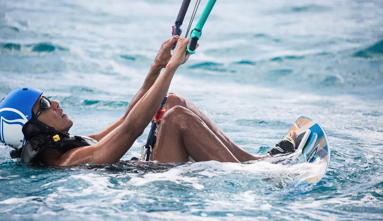 Barack Obama bersiap menjajal kite surfing saat liburan di Kepulauan Karibia, Selasa (7/2). Obama dijamu oleh miliarder Richard Branson saat berlibur di Karibia. (AP/Jack Brockway)