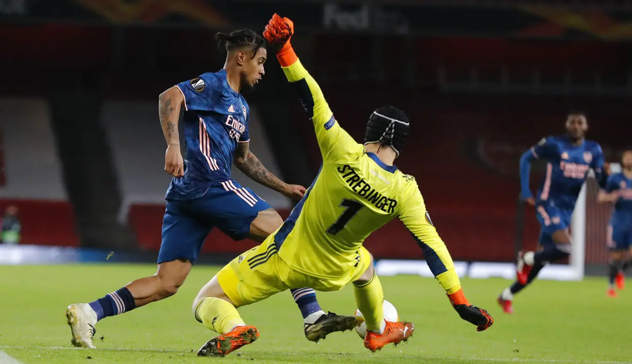 Pemain Arsenal Reiss Nelson duel bola dengan kiper Rapid Wien Richard Strebinger pada pertandingan Grup B Liga Europa di Emirates Stadium, London, Inggris, Kamis (3/12/2020). Arsenal menyegel status juara Grup B Liga Europa usai menaklukkan Rapid Wien 4-1. (AP Photo/Frank Augstein)