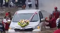 Sebuah mobil pengantin terpaksa harus didorong warga demi keluar dari jebakan banjir (dok.Liputan6.com/Vidio.com)