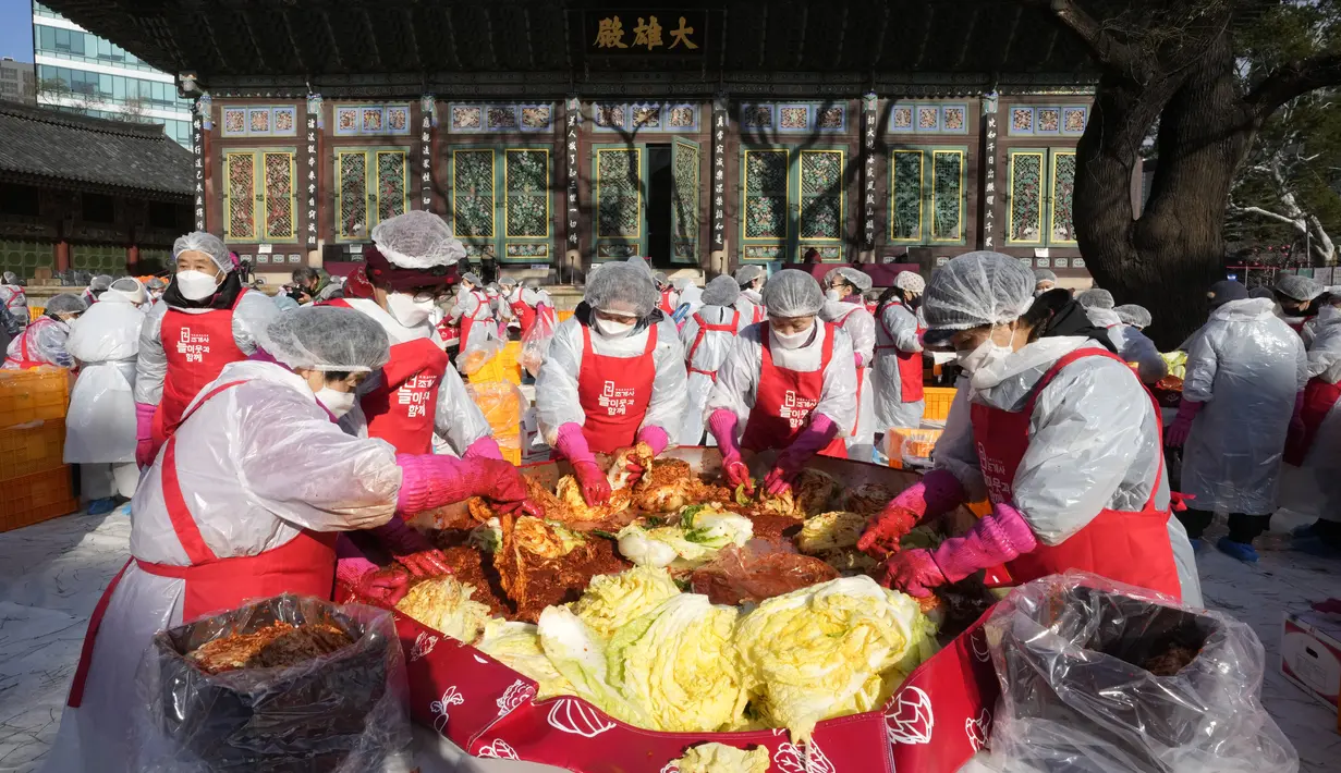 Relawan membuat kimchi untuk disumbangkan kepada tetangga yang membutuhkan, di sebuah kuil di Seoul, Korea Selatan, Kamis (2/12/2021). Sekitar 200 orang membuat 4.000 bungkus kimchi, dibuat dari fermentasi sayuran, seperti sawi putih, lobak, yang diberi bumbu pedas. (AP Photo/Ahn Young-joon)