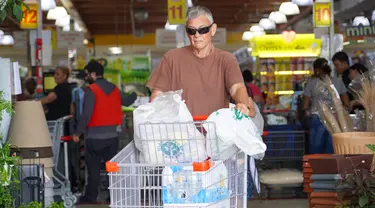 Seorang pria membeli perbekalan dan makanan yang tidak mudah rusak di supermarket sebagai persiapan menghadapi datangnya Badai Tropis Ernesto, di San Juan, Puerto Riko, Selasa (13/8/2024). (Jaydee Lee SERRANO / AFP)