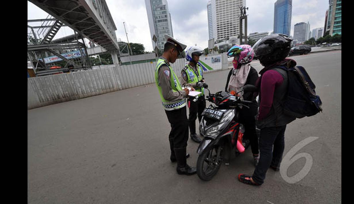 Polisi menghentikan pemotor yang ingin melintasi jalan protokol dari MH Thamrin-Medan Merdeka Barat, Jakarta, Minggu (18/1). (Liputan6.com/Miftahul Hayat) 