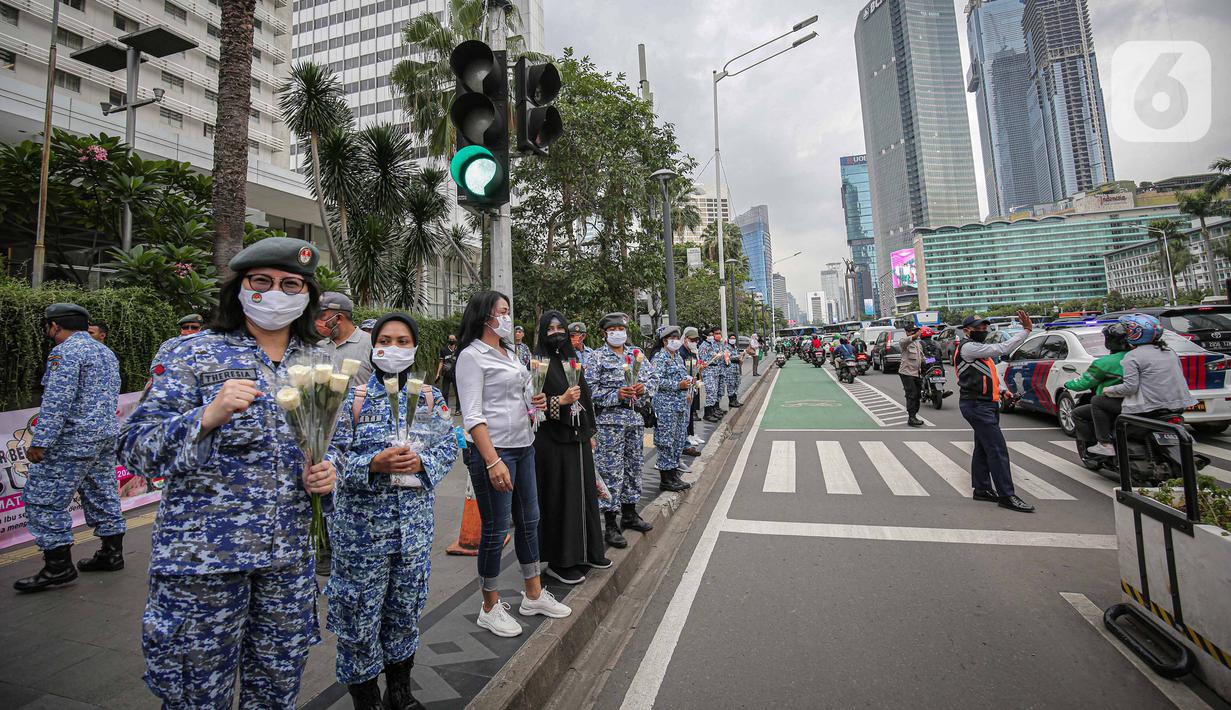 Perserta yang tergabung dalam Forum Kader Bela Negara DKI Jakarta saat membagikan bunga dan masker kepada pengguna jalan di Jalan Thamrin, Jakarta, Rabu (22/12/2021). Aksi tersebut merupakan bentuk apresiasi terhadap kaum perempuan terutama pada peringatan Hari Ibu. (Liputan6.com/Faizal Fanani)