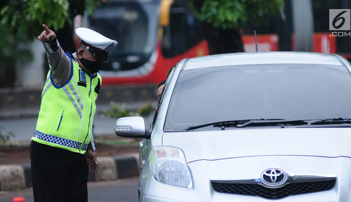 Petugas kepolisian mengarahkan kendaraan saat pengalihan arus di Jalan Jenderal Sudirman, Jakarta, Minggu (31/12). Pengalihan terkait malam puncak perayaan pergantian tahun di kawasan Bundaran HI hingga Jalan MH Thamrin. (Liputan6.com/Helmi Fithriansyah)