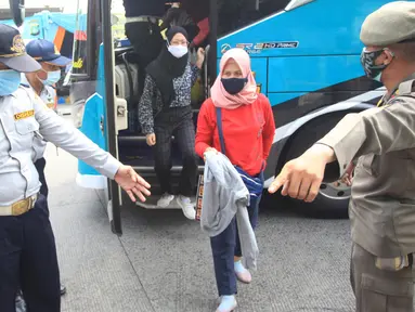 Petugas mengarahkan penumpang yang turun dari bus Antar Kota Antar Provinsi (AKAP) di Terminal bus Kalideres, Jakarta Barat, Senin (17/5/2021). Arus balik pemudik mulai terlihat di sejumlah terminal di Jakarta, salah satunya di Terminal Kalideres. (Liputan6.com/Angga Yuniar)