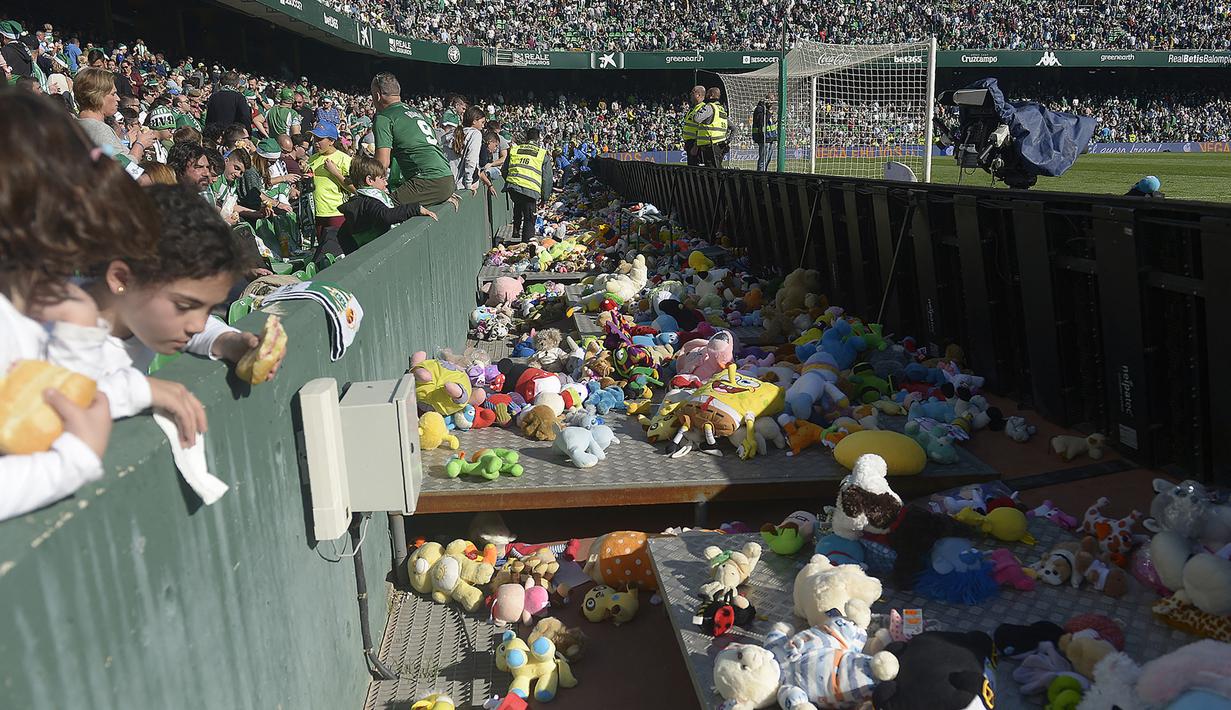 Tradisi yang entah sejak kapan dimulai bertujuan untuk mengumpulkan mainan atau boneka yang akan didonasikan kepada para anak yang membutuhkan menjelang perayaan Natal di Spanyol. Pada 2018, tradisi ini juga pernah dilakukan para suporter Real Betis sebelum pandemi COVID-19. (AFP/Cristina Quicler)