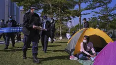 Petugas polisi membawa spanduk yang menunjukkan jarak sosial untuk mencegah penyebaran virus corona kepada pengunjung di sebuah taman di Hong Kong, Sabtu (2/1/2021). Diketahui, varian baru virus corona Inggris ditemukan di Hong Kong. (AP Photo/Vincent Yu)