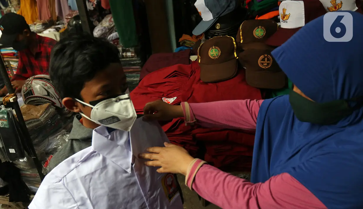 Pembeli mencoba seragam sekolah untuk anaknya di Pasar Mester, Jakarta , Minggu (29/8/2021). Menurut pedagang, penjualan seragam sekolah kembali meningkat hingga 30 persen jelang masuk sekolah tatap muka yang dilaksanakan kembali pada 30 Agustus 2021. (Liputan6.com/Herman Zakharia)