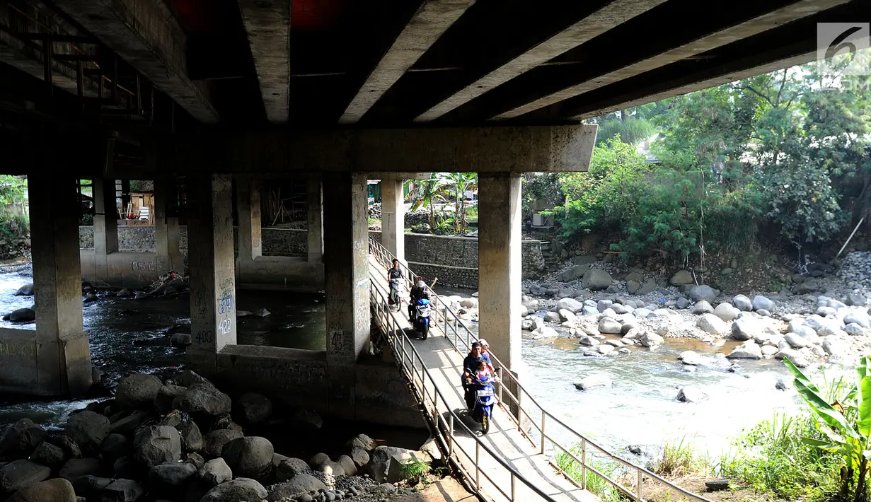 Pengendara motor melewati jembatan Ciliwung yang berada di bawah tol ruas Gadog, Ciawi, Bogor (16/68). Jembatan ini menjadi jalan alternatif bagi pemotor dari kawasan Bogor menuju arah Puncak dan Sukabumi. (Merdeka.com/Arie Basuki)