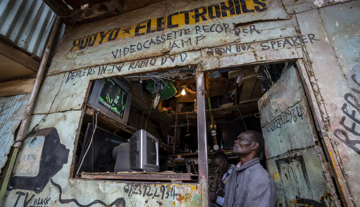 Seorang pria menonton berita pemilu di televisi di sebuah bengkel elektronik di daerah Kibera, Nairobi, Kenya, Kamis, 11 Agustus 2022. Rakyat Kenya menunggu hasil pemilihan presiden yang berlangsung ketat namun tenang di mana jumlah pemilih lebih rendah daripada biasanya. (AP Photo/Ben Curtis)