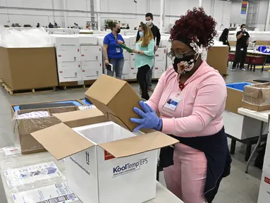 Seorang karyawan di distributor McKesson Corporation mengemas sekotak vaksin Johnson & Johnson ke dalam pendingin untuk dikirim di Shepherdsville, Kentucky, Senin (1/3/2021). Vaksin Covid-19 Johnson & Johnson menjadi vaksin corona ketiga yang sah digunakan di AS. (AP Photo/Timothy D. Easley, Pool)