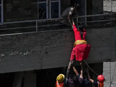Personel kepolisian mengevakuasi warga yang terjebak dari sebuah rumah yang tertimbun lumpur akibat banjir bandang di Trishuli, Distrik Nuwakot, Nepal, Kamis, pada 27 Agustus 2026. (AFP/ Arun Sankar)