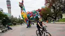 Pesepeda melintas dekat llama raksasa, bagian dari seni instalasi "Hecho en Casa" di kota Santiago, Chile, Senin (29/10). llama setinggi delapan meter itu dibuat oleh para sneiman dari sekolah Embroidery 2 asal Portugal. (Martin BERNETTI/AFP)