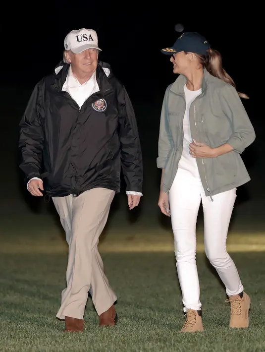 Presiden AS Donald Trump dan ibu negara, Melania Trump setibanya di Gedung Putih usai kunjungan ke Puerto Rico, Selasa (3/10). Celana putih yang dikenakan Melania dinilai kembali menunjukkan bahwa ia tak ingin kotor. (AP Photo/Pablo Martinez Monsivais)