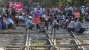 Demonstran duduk di rel kereta api setelah memblokir rel kereta api selama protes terhadap kudeta militer di Mandalay, Myanmar (17/2/2021). Aksi protes tersebut menghentikan layanan kereta api antara Yangon dan kota selatan Mawlamyine. (AP Photo)