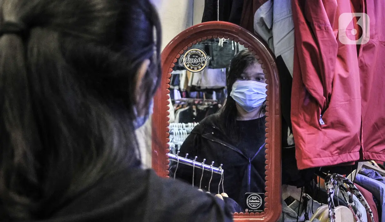 Pengunjung melihat cermin saat menjajal pakaian bekas impor di Pasar Senen, Jakarta, Kamis (4/3/2021). Rudi (34) salah satu pedagang mengungkapkan penjualan pakaian bekas impor di Pasar Senen merosot hingga 50 persen sejak awal pandemi COVID-19 melanda Ibu Kota. (merdeka.com/Iqbal S. Nugroho)