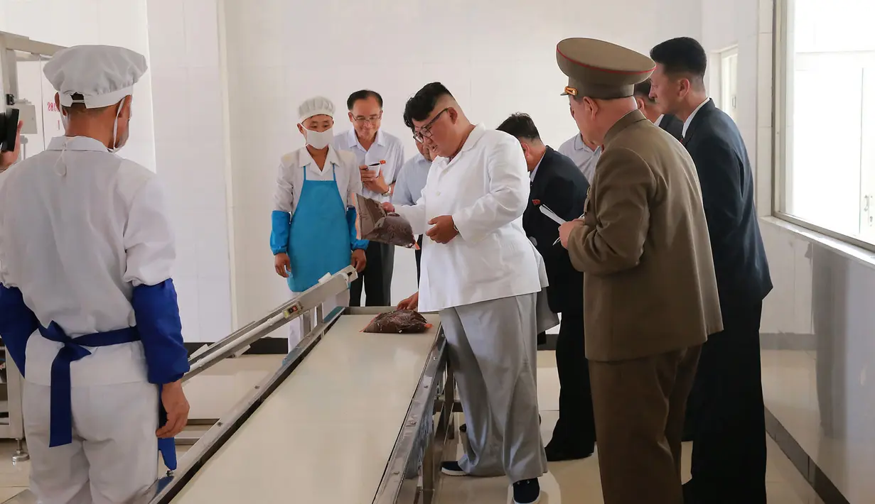 Pemimpin Korea Utara Kim Jong-un (tengah) memeriksa salah satu produk ransum militer saat mengunjungi Pabrik No. 525 di Korea Utara, Rabu (25/7). (STRINGER/AFP/KCNA VIA KNS)
