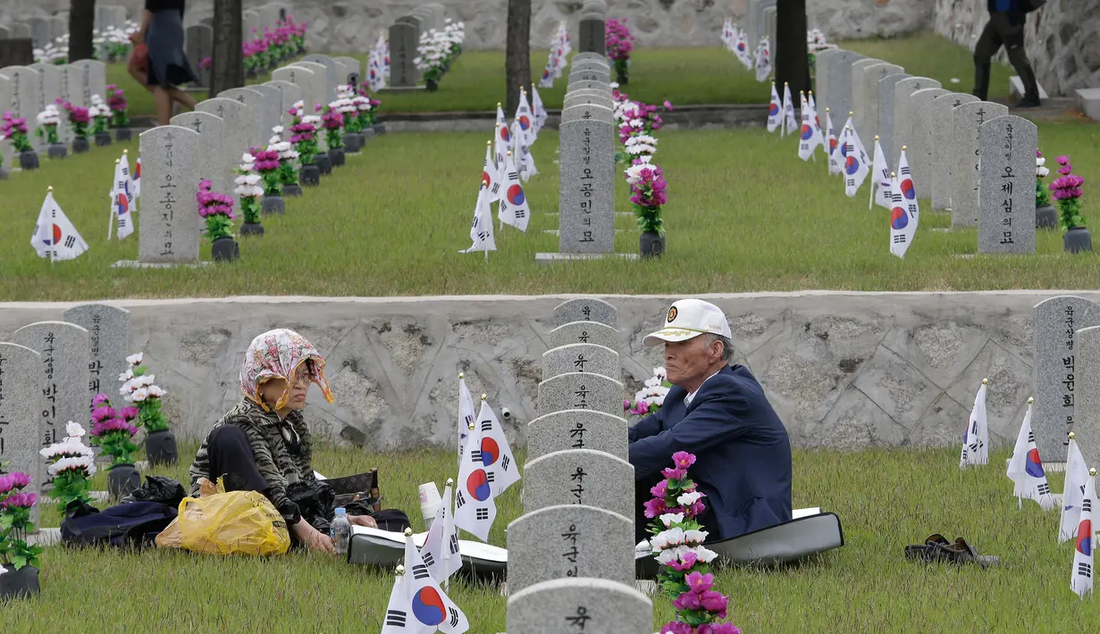 Sepasang suami istri duduk di depan nisan saudara lelakinya, Song Hyun-won, yang gugur untuk negara pada Memorial Day di Pemakaman Nasional Seoul, Kamis (6/6/2019). Memorial Day didedikasikan untuk mengingat prajurit dan warga sipil yang gugur selama perang Korea antara 1950-1953 (AP/Ahn Young-joon)
