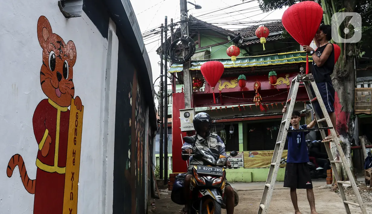 Warga menghias jalan dengan lampion di Kampung Limo, Depok, Jawa Barat, Rabu (26/1/2022). Kampung dengan sejumlah warga keturunan Tionghoa tersebut menyambut perayaan Tahun Baru Imlek 2022 dengan menghias gapura dan jalan dengan pernak-pernik Imlek. (Liputan6.com/Johan Tallo)