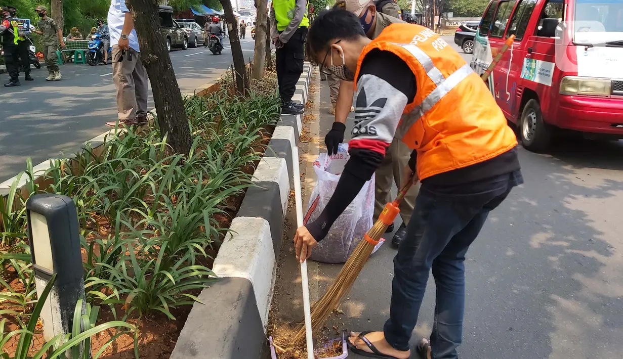 Warga menyapu jalan saat terkena razia masker di kawasan Karang Tengah Raya, Lebak Bulus, Jakarta, Senin (14/9/2020). Penertiban terkait pelaksanaan PSBB Jakarta kembali dan memutus rantai penyebaran COVID 19. (Liputan6.com/Faizal Fanani)