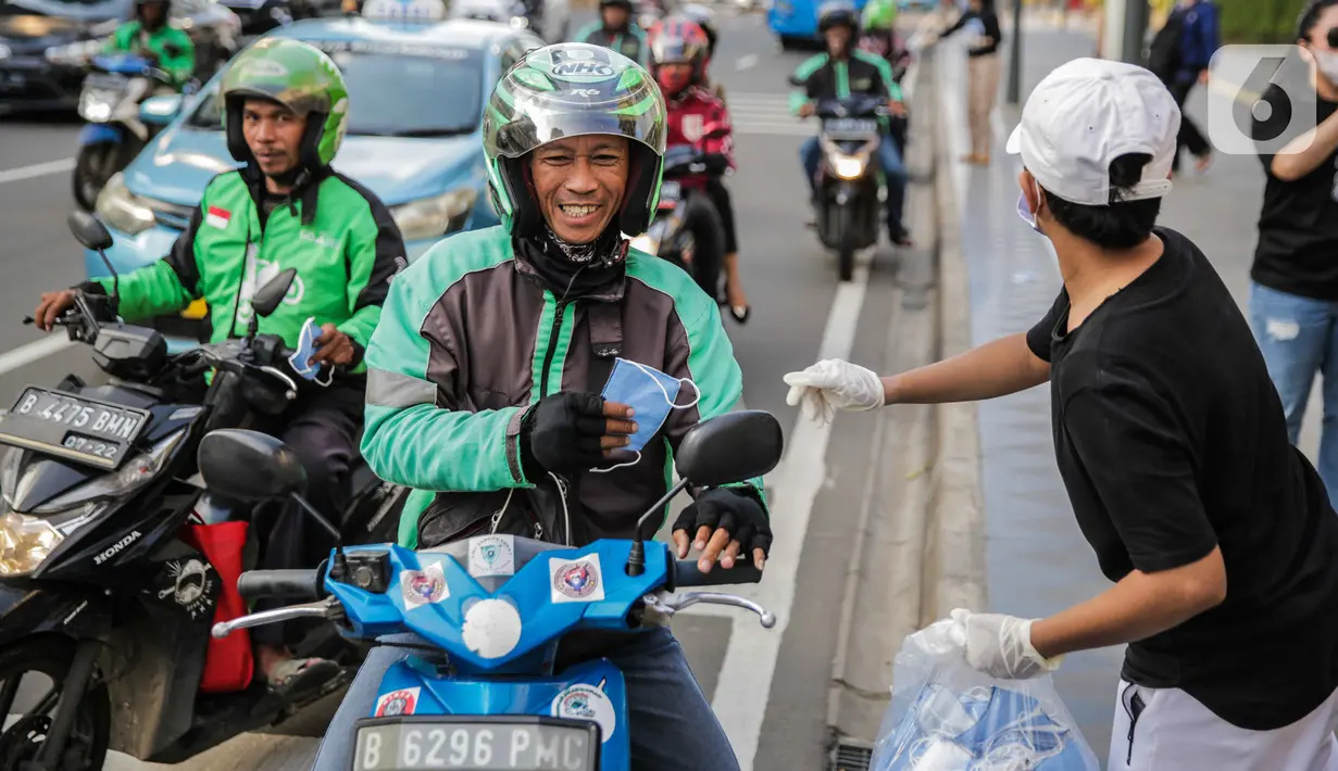 Relawan membagikan masker kepada pengemudi ojek online di Bundaran HI, Jakarta, Selasa (17/3/2020). Sebanyak 3.000 masker dibagikan secara gratis sebagai salah satu bentuk keprihatinan sekaligus berpartisipasi dalam upaya mencegah penyebaran virus corona COVID-19. (Liputan6.com/Faizal Fanani)