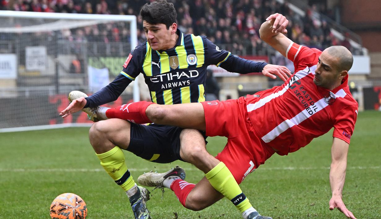 Pemain Manchester City, Abdukodir Khusanov, berebut bola dengan pemain Leyton Orient,Darren Pratley, dalam laga putaran keempat FA Cup 2024/2025 yang dihelat di Brisbane Road, London, Sabtu (8/2/2025) malam WIB. (AFP/Justin Tallis)