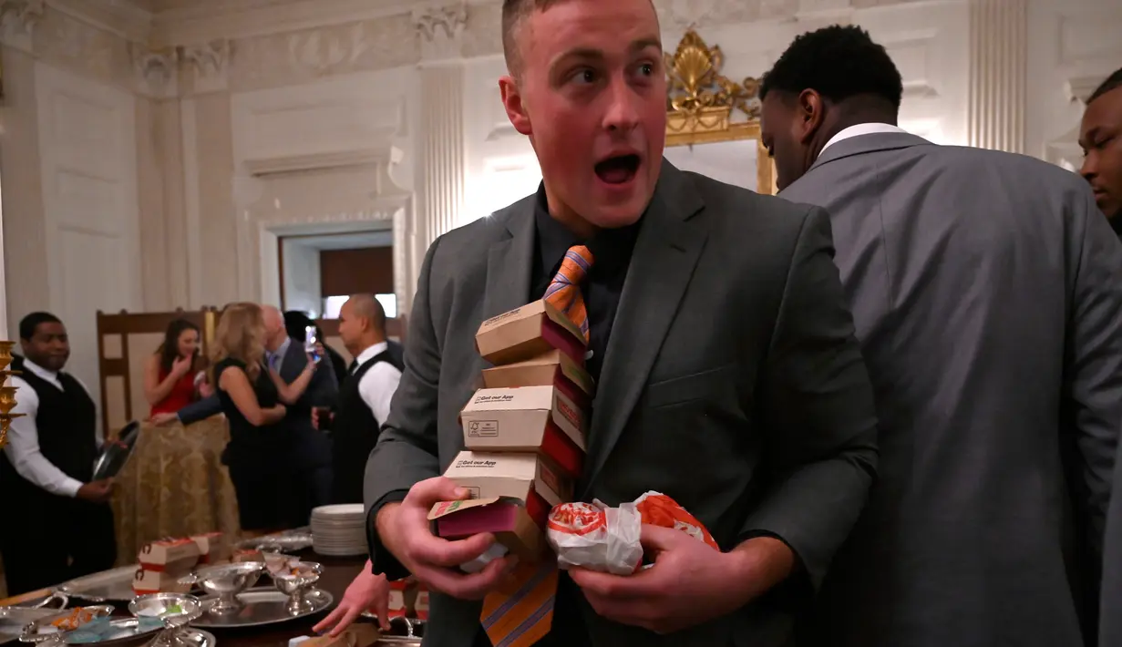 Tamu mengambil makanan cepat saji saat Presiden AS Donald Trump menjamu Clemson Tigers di Gedung Putih, Washington, Senin (14 /1). Makanan cepat saji dipilih karena staf katering Gedung Putih telah dirumahkan. (AP Photo/Susan Walsh)