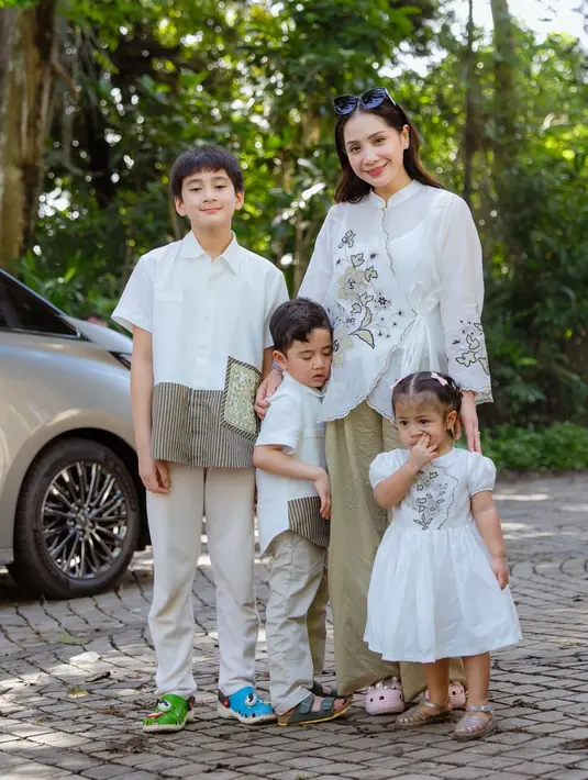 Nagita Slavina tampil dengan atasan putih model tali samping dihiasi bordiran bunga. Tampilannya kompak dengan ketiga anaknya. [@raffinagita1717]