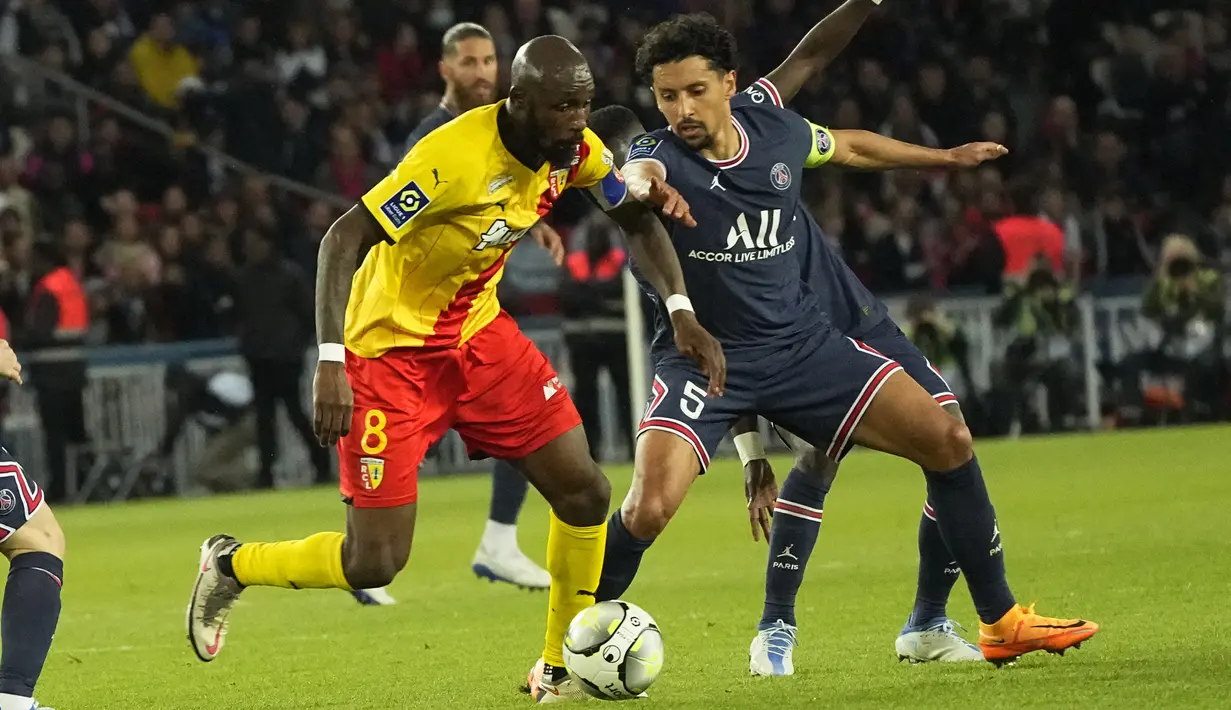 <p>Bek Paris Saint-Germain (PSG) Marquinhos berebut bola dengan gelandang Lens Seko Fofana dalam pekan ke-34 Ligue 1 di Parc des Princes, Minggu (24/4/2022) dini hari WIB. PSG sudah memastikan gelar juara Ligue 1 Prancis berkat hasil imbang 1-1 dengan tamunya Lens. (AP Photo/Michel Euler)</p>