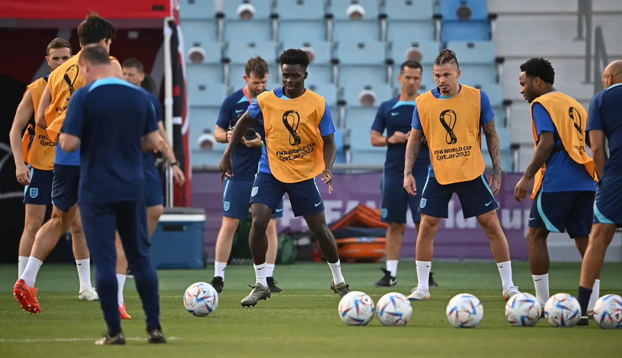 Penyerang Inggris #17 Bukayo Saka (Tengah) dan rekan satu timnya ambil bagian dalam sesi latihan jelang kontra Prancis pada perempat final Piala Dunia 2022, di Stadion Al Wakrah SC, selatan Doha, Jumat (9/12/2022). Kemenangan menjadi harga mutlak untuk didapatkan kedua tim demi mendapatkan tempat di babak semifinal. (Paul ELLIS / AFP)