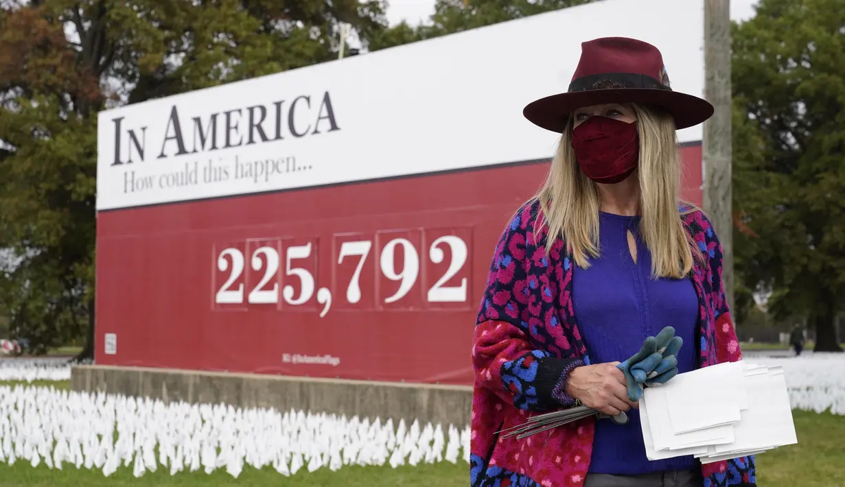 Seniman Suzanne Brennan Firstenberg berdiri dekat instalasi seni berupa bendera putih yang ditanam untuk mengenang warga Amerika yang meninggal karena COVID-19 di dekat Stadion RFK, Washington, Selasa (27/10/2020). Setiap bendera mewakili satu nyawa yang hilang akibat Covid-19. (AP/Patrick Semansky)