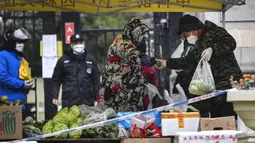 Warga membeli produk dari pasar sementara di pintu masuk area perumahan yang dikarantina, Kota Xi'an, Provinsi Shaanxi, China, 25 Desember 2021. Xi'an lockdown ketat dengan hanya satu orang per rumah tangga yang diizinkan keluar setiap dua hari untuk berbelanja kebutuhan. (Tao Ming/Xinhua via AP)