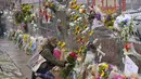 Seorang pelayat meninggalkan karangan bunga di sepanjang pagar yang dipasang di sekitar tempat parkir tempat penembakan massal terjadi di toko kelontong King Soopers Selasa, 23 Maret 2021, di Boulder, Colo. (Foto AP / David Zalubowski)