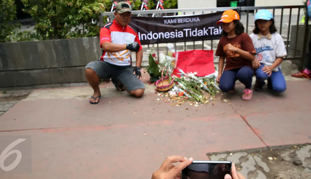 Warga berfoto di dekat poster #Indonesiatidaktakut yang dipasang di depan Menara Cakrawala, Jakarta, Sabtu (16/1). Lokasi teror di kawasan Sarinah Thamrin terus didatangi warga untuk mengabadikan diri atau foto selfie. (Liputan6.com/Faizal Fanani)