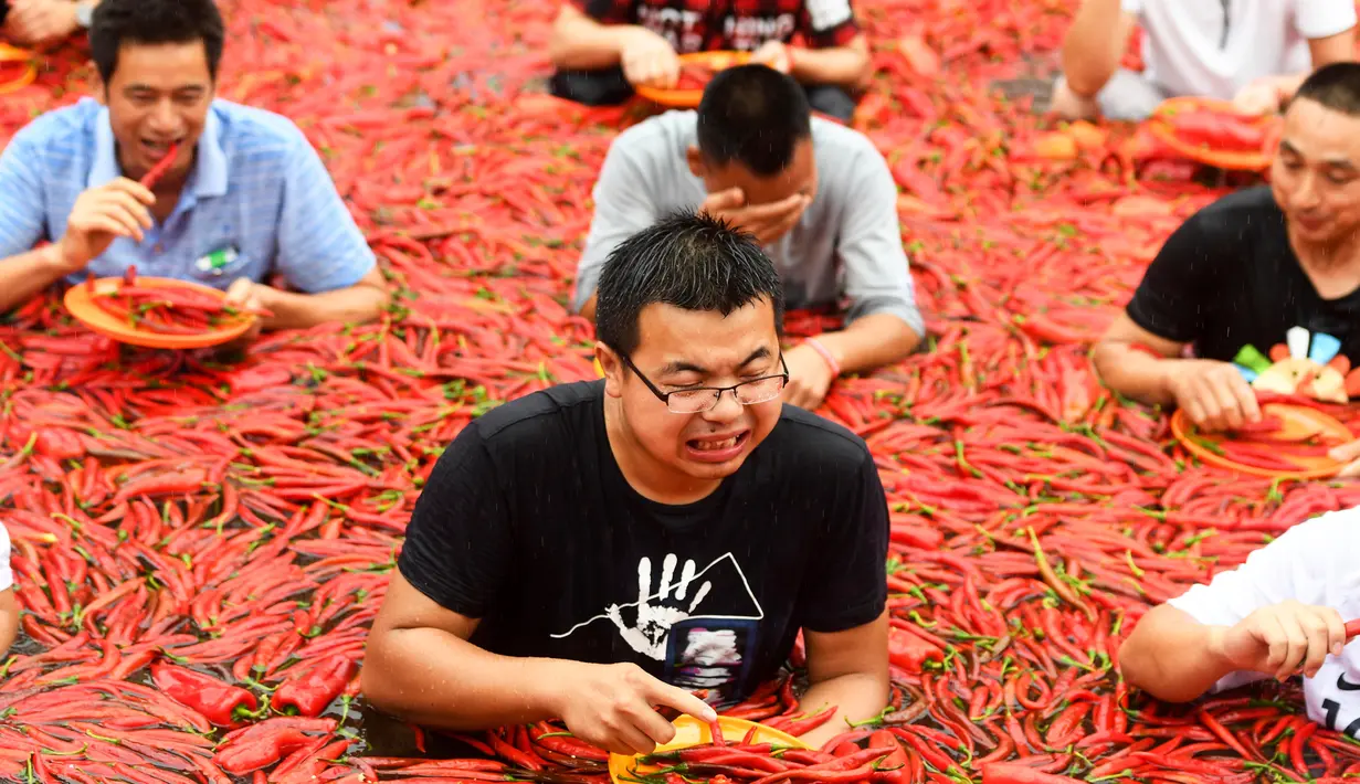 Sejumlah kontestan memakan cabai saat mengambil bagian dalam kompetisi makan cabai di Ningxiang di provinsi Hunan tengah, China (8/7). Pemenang dalam kontes ini telah memakan 5 cabai dalam waktu satu menit. (AFP Photo)