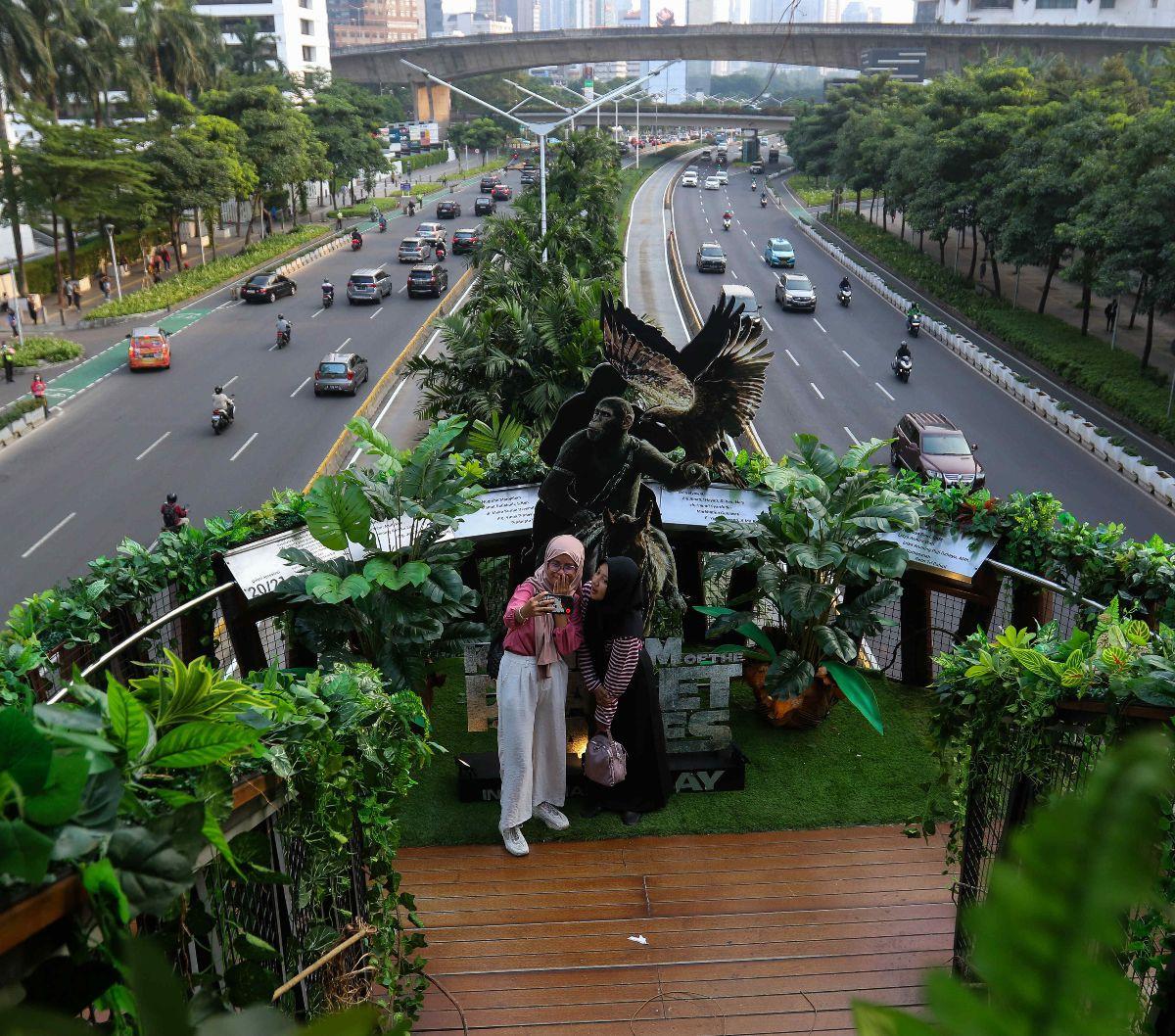 Warga berswafoto di Jembatan Penyeberangan Orang (JPO) Phinisi di Jalan Jenderal Sudirman, Jakarta, Jumat (10/5/2024). JPO Phinisi tiba-tiba menjelma bak hutan belantara. Jembatan estetik itu dipenuhi dedaunan dan akar-akar tumbuhan yang menjuntai. Liputa