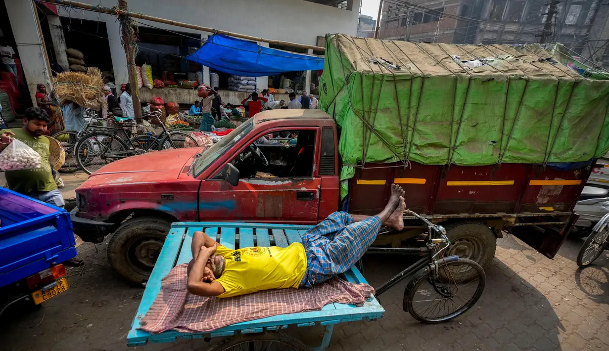 Seorang pria beristirahat di atas gerobak dorong di sebuah pasar grosir sayuran di Guwahati, India, Rabu, 1 Februari 2023. Pemerintah Perdana Menteri India Narendra Modi meningkatkan belanja modal sebesar 33% menjadi $122 miliar dalam anggaran tahunan yang diajukan ke Parlemen pada hari Rabu, untuk memacu pertumbuhan ekonomi dan menciptakan lapangan kerja menjelang pemilihan umum tahun depan. (AP Photo/Anupam Nath)
