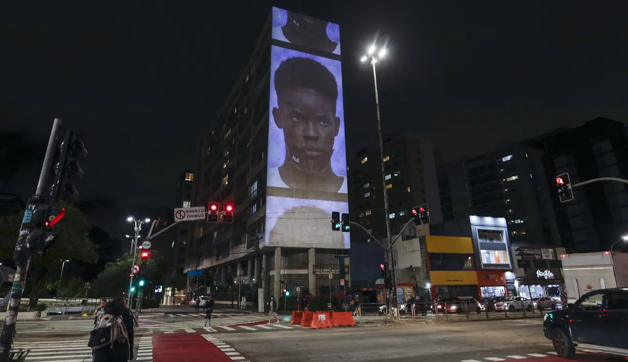 Model mengenakan kreasi dari koleksi Alexandre Herchcovitch yang diproyeksikan pada sebuah gedung selama Sao Paulo Fashion Week, Rabu (4/11/2020). Perancang busana meninggalkan catwalk dan mengandalkan teknologi digital untuk memamerkan karya koleksi spring/summer mereka. (AP Photo/Marcelo Chello)
