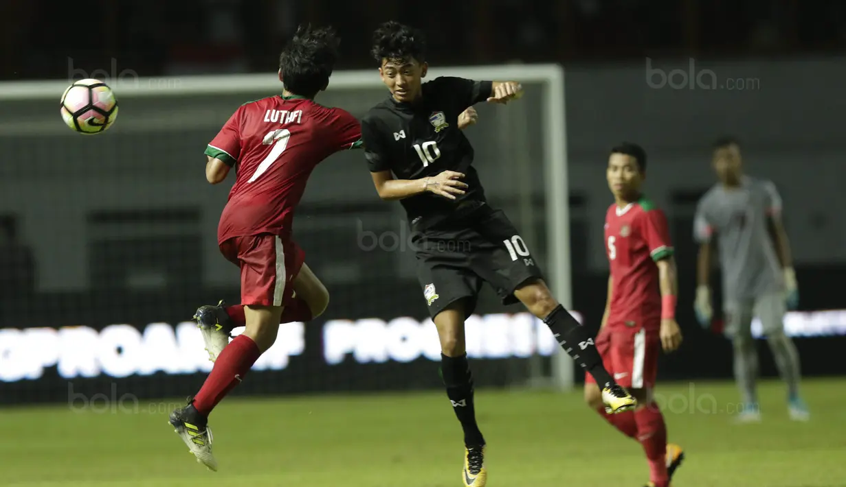 Gelandang Indonesia U-19, M Luthfi, duel udara dengan pemain Thailand U-19, Korawich Tasa, pada laga persahabatan di Stadion Wibawa Mukti, Cikarang, Minggu (8/10/2017). Indonesia menang 3-0 atas Thailand. (Bola.com/M Iqbal Ichsan)
