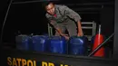Petugas membawa jerigen yang berisi bahan untuk miras oplosan saat melakukan penggerebekan di Cicalengka, Bandung, Minggu (8/4).  Sebanyak 15 dari 27 nyawa melayang usai meneguk minuman keras (miras) oplosan di Cicalengka. (Timur Matahari/AFP)