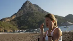 Seorang wanita berlatih yoga di pantai di Adrasan, barat Antalya, Turki (24/9/2021). Orang-orang menikmati cuaca hangat di wilayah Mediterania saat salju pertama menyelimuti pegunungan tinggi di timur laut Turki. (AP Photo/Burhan Ozbilici)