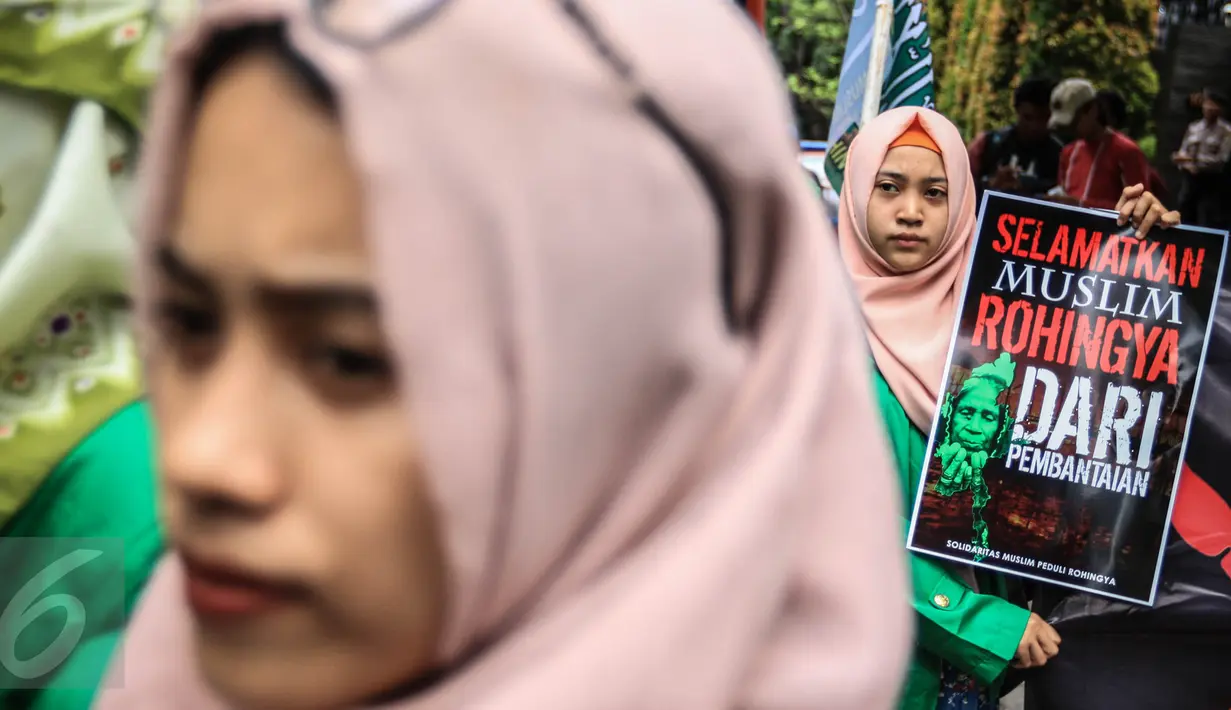 Seorang peserta aksi dari Solidaritas Muslim Rohingya (SMR) menunjukkan poster di depan Kedubes Myanmar, Jakarta, Jumat (25/11). Pengunjuk rasa membawa spanduk sambil berorasi soal pembantaian kaum muslim Rohingya di Myanmar. (Liputan6.com/Faizal Fanani)