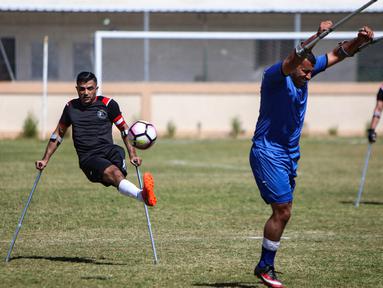 Seorang pemain klub Al-Jazeera (hitam) menendang bola dalam pertandingan final kejuaraan lokal sepak bola korban amputasi melawan Al-Abtal yang diselenggarakan oleh Komite Palang Merah Internasional (ICRC), di tengah pandemi COVID-19, di Kota Gaza, Palestina, (18/3/2021). (AFP/Mohammed Abed)