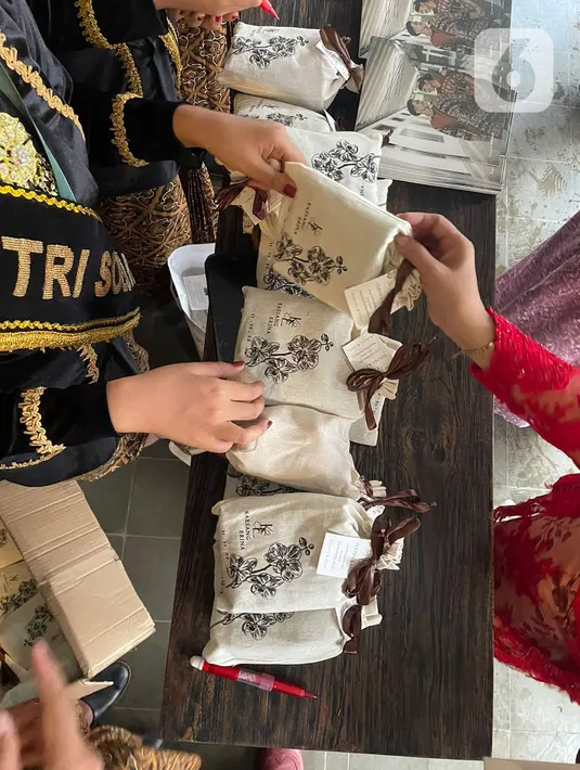Tamu undangan mendapatkan souvenir pernikahan Kaesang Pangarep dan Erina Gudono di Pura Mangkunegaran, Solo, Minggu (11/12/2022). Antrean tamu undangan yang ingin berfoto dengan Kaesang Pangarep dan Erina Gudono beserta keluarga mengular panjang bahkan rela berdesak-desakan demi bisa berfoto dengan kedua mempelai. (Liputan6.com/Herman Zakharia)