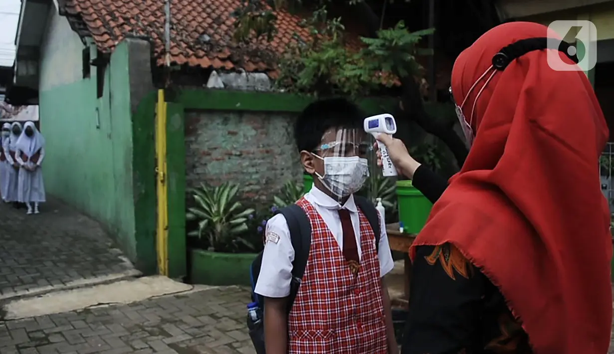 Guru memeriksa suhu tubuh murid sebelum memasuki ruang kelas saat pembelajaran tatap muka (PTM) terbatas di SDN Pisangan Baru 05 Pagi, Jakarta, Senin (8/11/2021). Pembekalan pemahaman protokol kesehatan dilakukan seiring penambahan jumlah sekolah tatap muka terbatas. (merdeka com/Iqbal S. Nugroho)