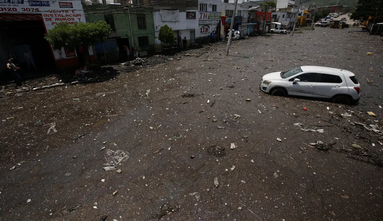 Pemandangan udara terlihat sebuah mobil yang terdampar di jalan berlumpur di Zapopan, negara bagian Jalisco, Meksiko (26/7/2021). Luapan sungai akibat guyuran hujan lebat menyebabkan banjir disertai lumpur dan sampah melanda Zapopan, sebuah kota di negara bagian Jalisco, Meksiko. (AFP/Ulises Ruiz)
