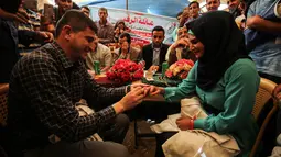 Petugas medis Muadh Al-Raqab memakaikan cincin kepada Hadeel Al-Najjar saat melangsungkan prosesi pernikahan di dalam tenda jalur Gaza selatan, Palestina (2/5). (AFP Photo/Said Khatib)